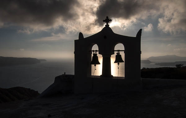 Santorini bells backlit by the setting sun